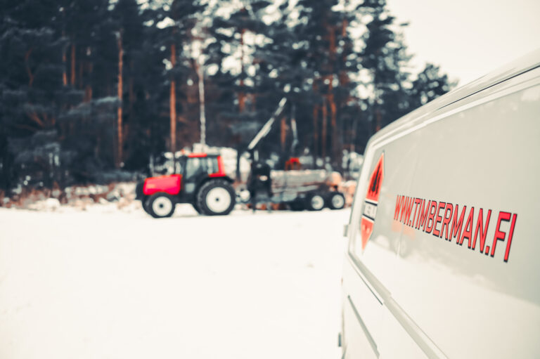 Vit bil med Timberman, skogstjänster i Västnyland, logo.